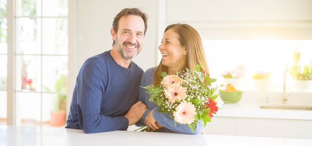 romantisches Paar mittleren Alters mit verliebten Blumen zu Hause - Foto, Bild