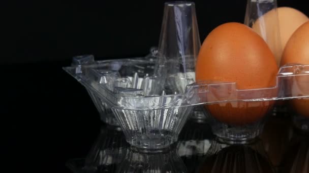 Grandes ovos de galinha marrom em uma bandeja de plástico transparente no fundo branco
 - Filmagem, Vídeo