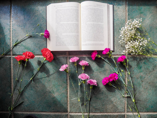 Colorful carnations with book and copy space on granite surface - Photo, image
