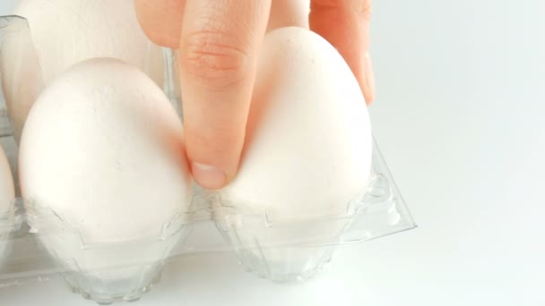 Μεγάλα λευκά αυγά κοτόπουλου σε διαφανές πλαστικό δίσκο σε λευκό φόντο - Πλάνα, βίντεο