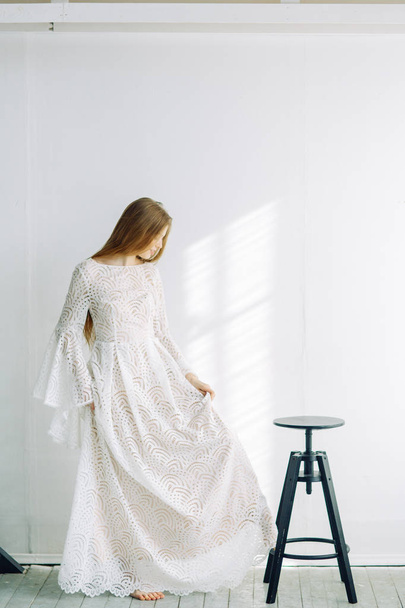 Beautiful bride sitting on a chair in the white Studio. Minimalistic wedding in European style. - Foto, afbeelding