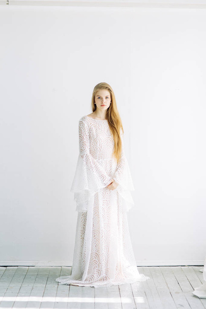 Beautiful bride on a white minimalistic background. Wedding preparations in fine art. - Valokuva, kuva