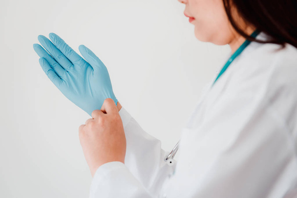 Lähikuva nainen lääkäri on yllään käsine kanssa stetoskooppi valkoinen eristetty tausta. Kirurgi ammatti, terveydenhuollon ja lääketieteen käsite
. - Valokuva, kuva