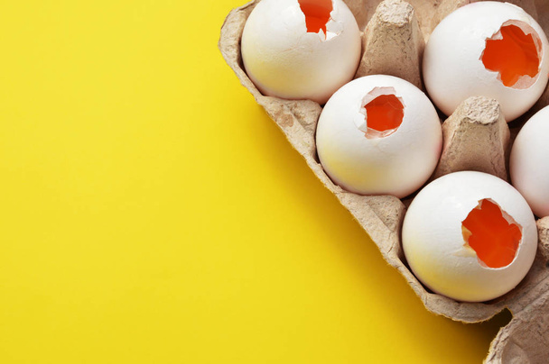 Zerbrochene Eier im Eierkarton mit Kopierraum auf gelbem Hintergrund - Foto, Bild