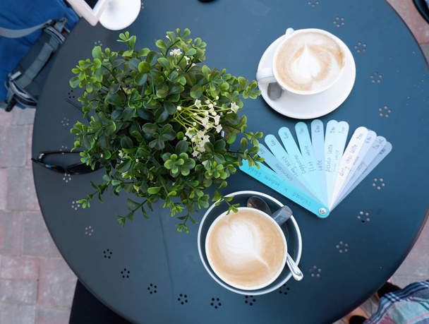 青のテーブルの上のいろいろな飲み物の名前そしてコーヒーのコップが付いている青い板メニュー - 写真・画像