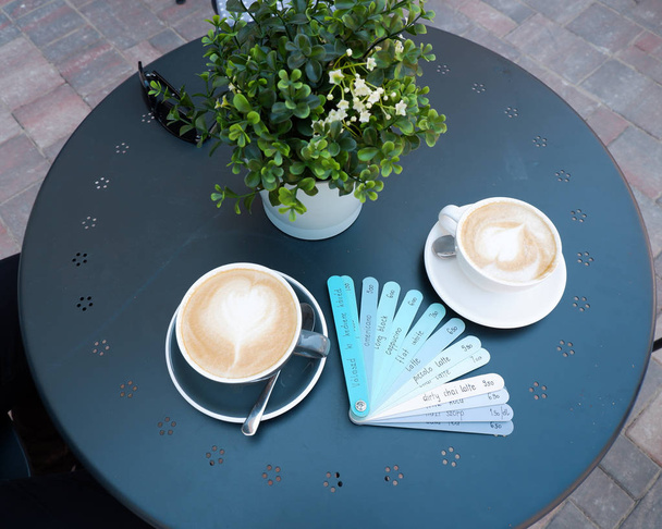 menu pranchas azuis com vários nomes de bebidas e xícaras de café na mesa azul
 - Foto, Imagem