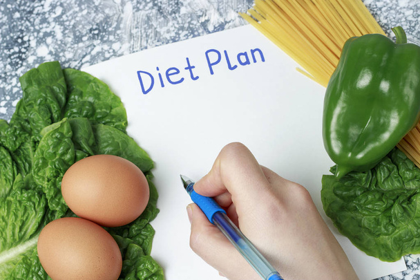 Plan de dieta de inscripción en hoja blanca y alimentos saludables, mano de escritura. Vista desde arriba
 - Foto, imagen