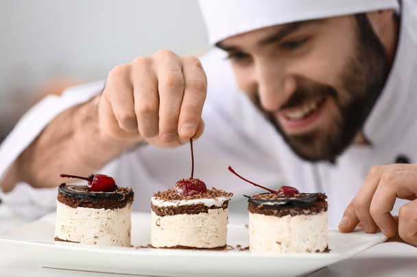 Confiseur masculin décorant dessert savoureux dans la cuisine, gros plan
 - Photo, image