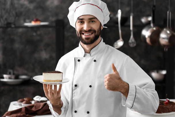 Male confectioner with piece of tasty cake in kitchen - Φωτογραφία, εικόνα