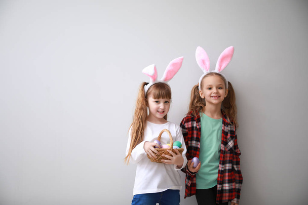 Милі маленькі діти з великодніми яйцями і вухами кролика на світлому фоні
 - Фото, зображення
