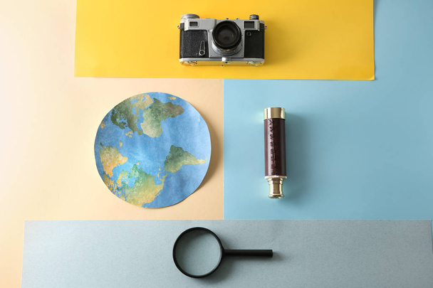 Papier aarde, fotocamera, Spyglass en vergrootglas op kleur achtergrond. Reis concept - Foto, afbeelding