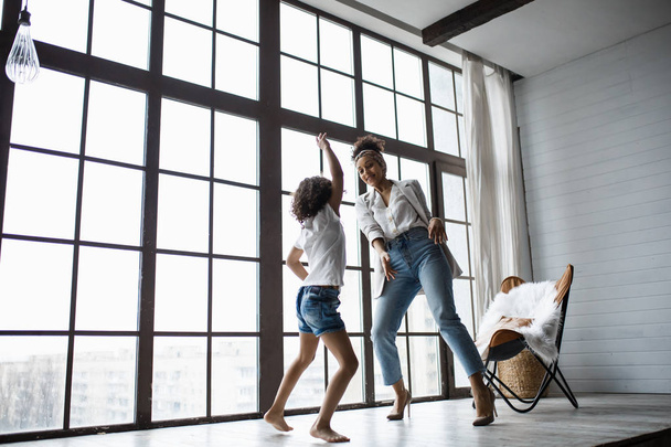 Šťastný, milující afro americké rodiny. Mladá matka a její dcera hraje v dětském pokoji. Máma a dcera se tančí na pozadí velkého okna - Fotografie, Obrázek