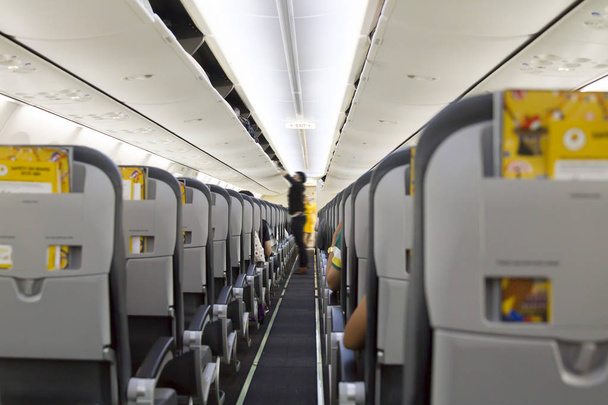 Intérieur de l'avion avec passagers sur les sièges et hôtesse de l'air en uniforme. Avion prêt pour la terre
.  - Photo, image
