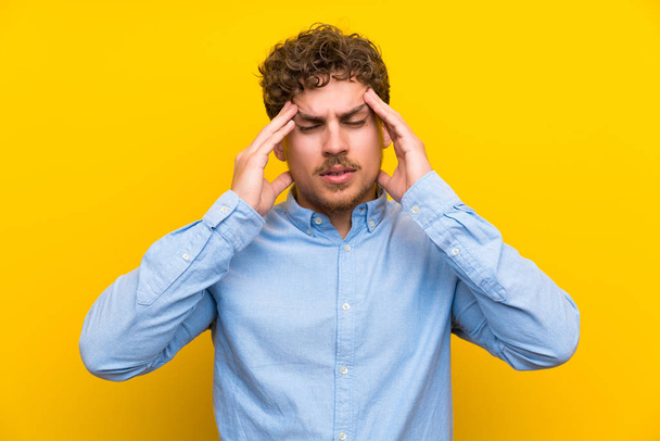 Blonde man over isolated yellow wall unhappy and frustrated with something. Negative facial expression - Photo, Image