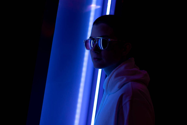 Low key portrait of a short haired woman in a neon light - Foto, afbeelding