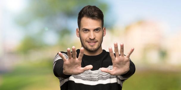 Όμορφος άνδρας καταμέτρηση δέκα με τα δάχτυλα σε εξωτερικούς χώρους - Φωτογραφία, εικόνα