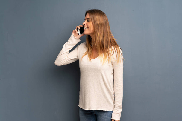 Donna bionda su sfondo grigio mantenere una conversazione con il telefono cellulare
 - Foto, immagini