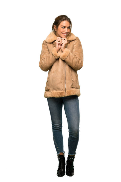 A full-length shot of a Blonde woman with a coat scheming something over isolated white background - Foto, immagini
