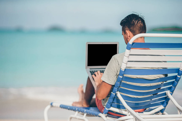 Hombre joven con tableta durante las vacaciones en la playa tropical - Foto, imagen