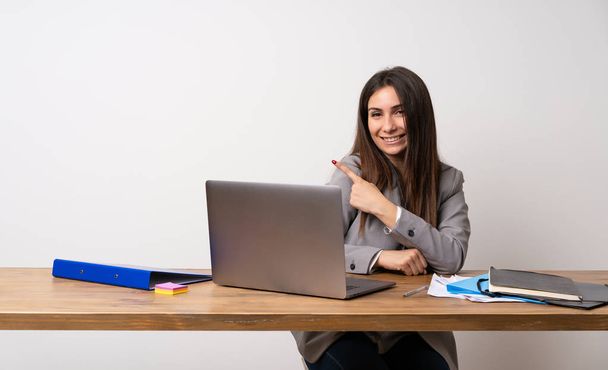 Деловая женщина в офисе, указывающая на сторону, чтобы представить продукт
 - Фото, изображение