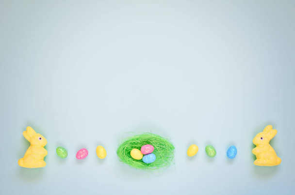 Easter holiday background with colorful shiny eggs and two yellow bunnies - Foto, Imagem
