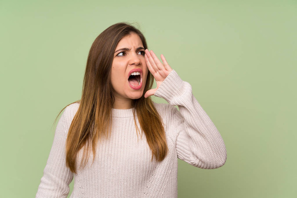Молодая девушка в белом свитере кричит с открытым ртом
 - Фото, изображение