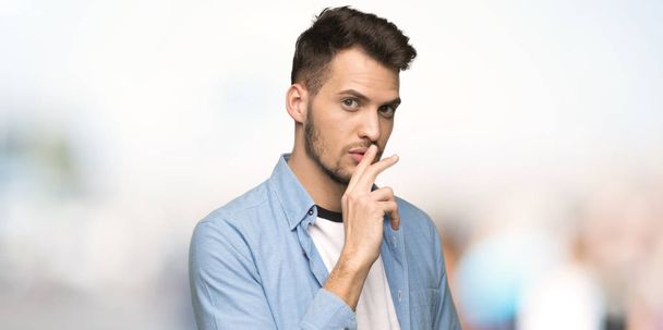 Komea mies osoittaa hiljaisuuden eleen laittamalla sormen suuhun ulkona
 - Valokuva, kuva