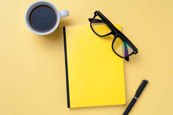 Coffee, notebook, eyeglasses and office stationery on bright yellow background - Zdjęcie, obraz