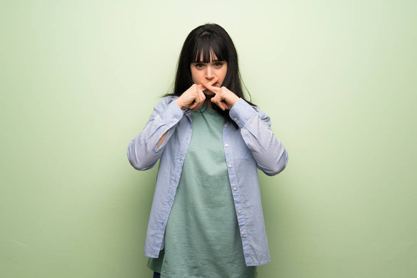 Mladá žena nad zelená zeď známek mlčení gesto - Fotografie, Obrázek