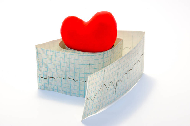 Idée photo arythmies et maladies cardiaques liées à des troubles du rythme cardiaque normal. Modèle coeur rouge se trouve sur le dessus du rouleau de papier électrocardiogramme sur un fond blanc
  - Photo, image