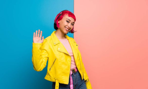 Young woman with yellow jacket saluting with hand with happy expression - Photo, Image