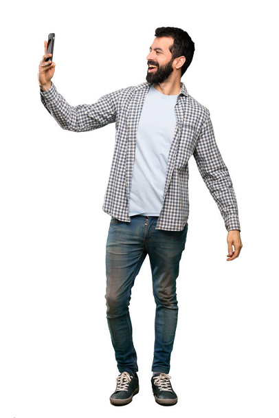 Bonito homem com barba fazendo uma selfie sobre fundo branco isolado
 - Foto, Imagem