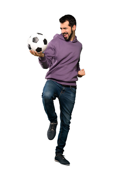 Όμορφος άνδρας με φούτερ κρατώντας μια μπάλα ποδοσφαίρου - Φωτογραφία, εικόνα
