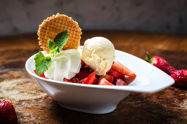 delicious ice cream with strawberries in bowl on table in cafe - Foto, imagen