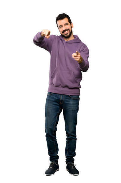 Full-length shot of Handsome man with sweatshirt points finger at you while smiling over isolated white background - Foto, Imagem