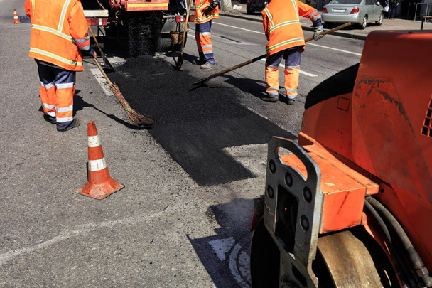 Het werk team vernieuwt een deel van het asfalt op de omheinde strook van de weg. - Foto, afbeelding