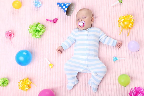 Baby boy with birthday decorations lying on pink bed - Foto, Imagem