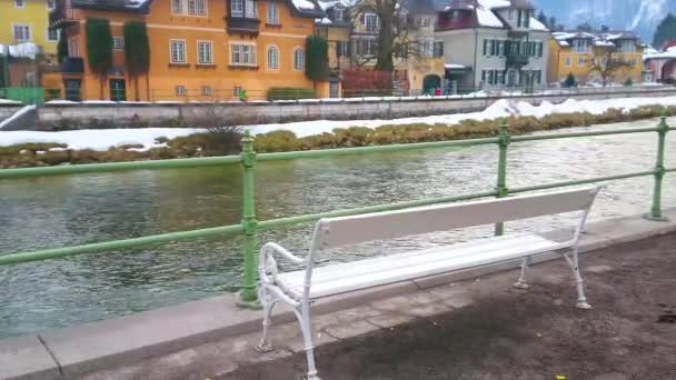 The white vintage bench in Esplanade embankment of Traun river with a view on Oscar Strauss Kai and old housing on the opposite bank, Bad Ischl, Salzkammergut, Austria.  - Video