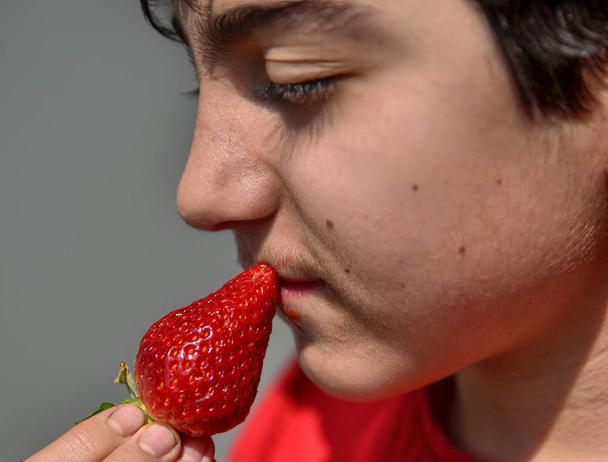 Caucasian child who is eating a strawberry - Zdjęcie, obraz