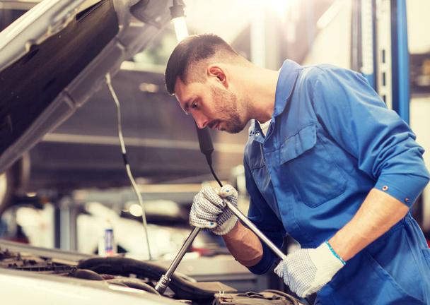 mechanic man with wrench repairing car at workshop - Фото, зображення