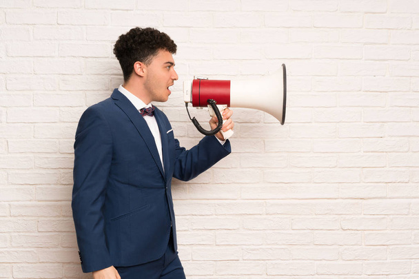 Man in suit and bow tie shouting through a megaphone - Photo, Image