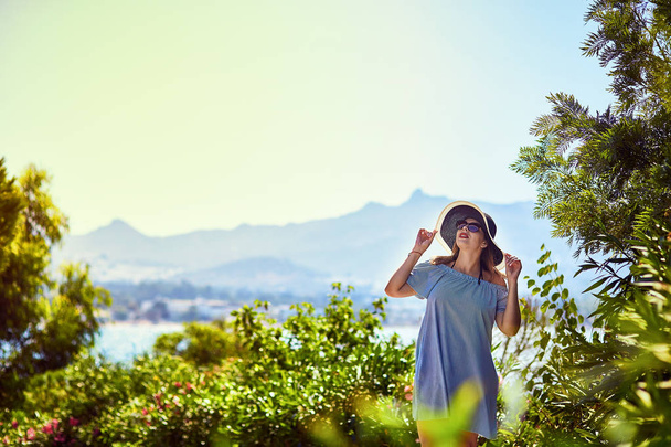 Hermosa mujer en sombrero de playa disfrutando de vistas al mar con cielo azul en el día soleado en Bodrum, Turquía. Vacaciones al aire libre Seascape Summer Travel Concept
 - Foto, Imagen