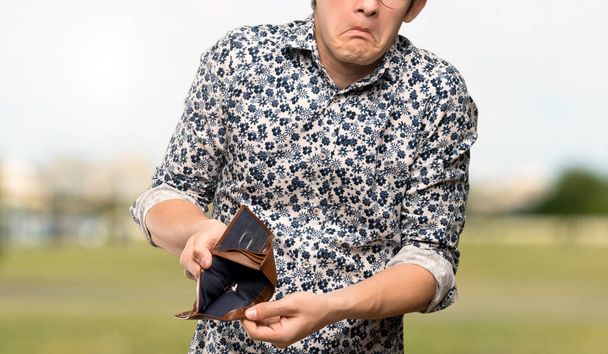 Homme adolescent avec chemise à fleurs et lunettes tenant un portefeuille à l'extérieur
 - Photo, image
