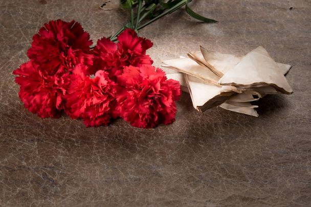 against the background of old paper, a bouquet of red carnations and envelopes - Foto, afbeelding