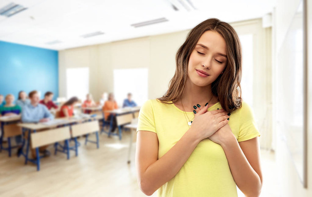 student girl holding hands on heart at school - Photo, image
