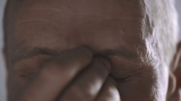 abgeschnittene Ansicht eines Mannes mittleren Alters, der in die Kamera schaut, blinzelt und sich die Augen reibt - Filmmaterial, Video