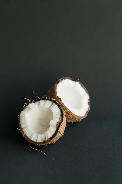 Broken ripe coconut on black background. White flesh - Foto, Imagem
