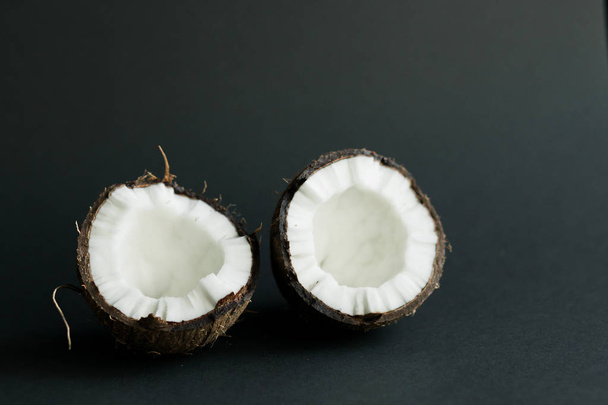 gebrochene reife Kokosnuss auf schwarzem Hintergrund. weißes Fruchtfleisch - Foto, Bild