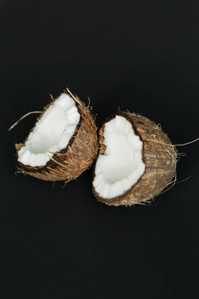 Broken ripe coconut on black background. White flesh - Photo, Image