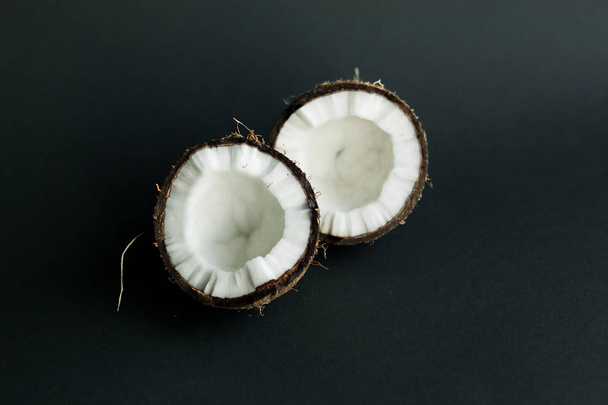 Broken ripe coconut on black background. White flesh - Фото, изображение